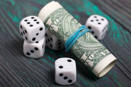 Dice are white. Near dollars rolled up in a tube. On brushed pine boards.