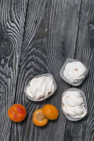 Marshmallows laid out on a tray. Nearby are ripe apricots.の写真素材