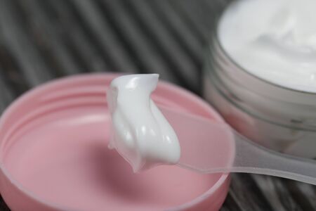 Plastic bottle with cream. The cover is removed and lies nearby. Near the shoulder blade, on it a...