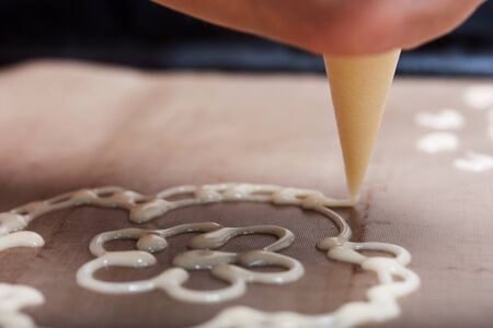 Woman makes a pattern of dough on a baking sheet. For the preparation of biscuit roll with spinach and mint. Stuffed with strawberries. Ingredients for cooking.の写真素材