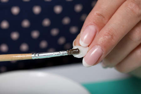 Roses with petals made of white polymer clay. A woman sticks them on a saucer. Crafts from polymer clay.の写真素材