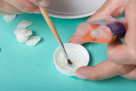 Roses with petals made of white polymer clay. Woman stirs glue with a brush. Crafts from polymer clay.の写真素材