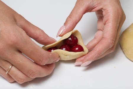 Woman wraps cherries in dough. Cooking dumplings. Close-up shot.の写真素材