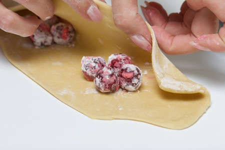 A woman wraps starchy cherries in a dough on the rolled dough. Cooking dumplings. Close-up shot.の写真素材