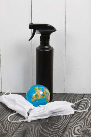 Antiseptic spray and protective mask for the duration of a pandemic. Among them lies a globe.