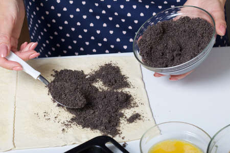 Woman sends poppy seeds puff pastry. For making puff pastry curls with poppy and walnut filling....