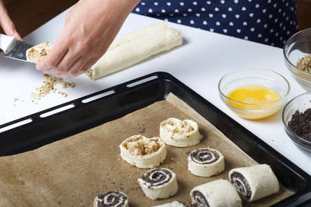 A woman cuts rolled puff pastry with a knife. Filled with poppy and walnuts. For making curls....