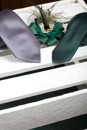 Two men's ties in different colors and sizes. Women's brooch. For father, mother and son. On painted boards.の写真素材