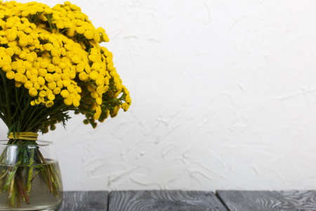 A bouquet of tansy in a glass goblet. On a white background.の写真素材