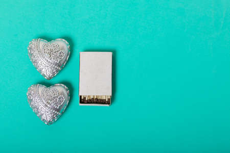 Two decorative candles in the shape of a heart. Next to them is a box of matches. Love and...