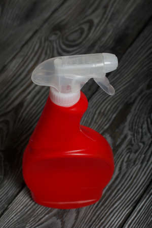 Red plastic bottle with spray. Cleaning spray. On painted pine planks.