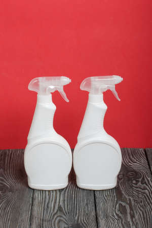 White plastic bottles with spray. Cleaning spray. On a coral background.