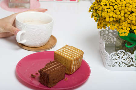 Two slices of honey cake. One of them is with chocolate. A woman eats dessert for Breakfast. Next to...
