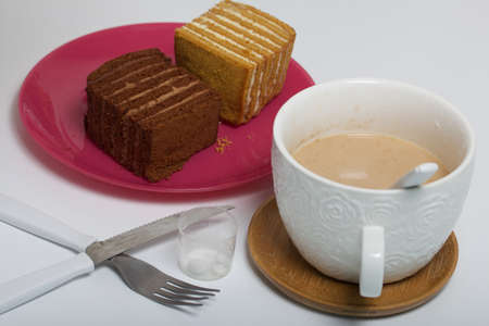Two slices of honey cake. One of them is with chocolate. Dessert for Breakfast. Next to it is a mug...