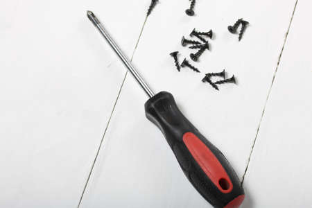 A screwdriver and a handful of screws. On white background.
