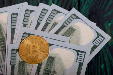 Golden bitcoin among dollar bills.
