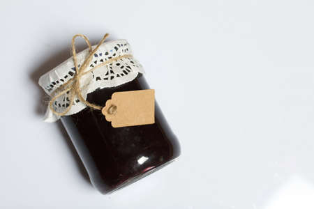 Jar of plum jam. With an inscription tag. On a white background.