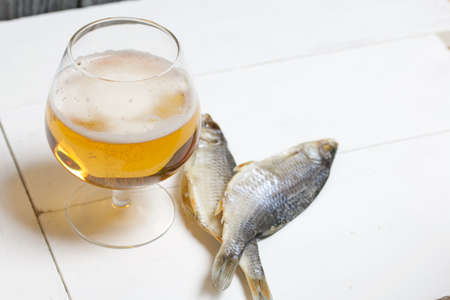 A glass of beer. Dried river fish lies nearby.の写真素材