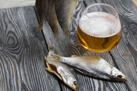 Dried river fish hangs on a rope. There is a glass of beer nearby.の写真素材