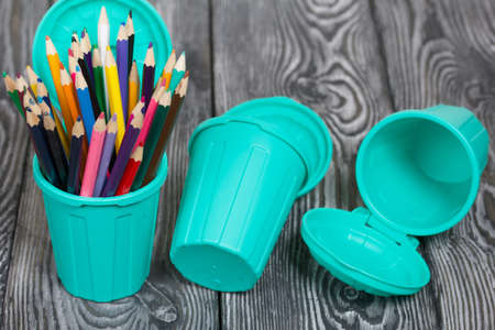 Colored pencils in a pencil holder. Dumpster-shaped pencils. On brushed pine boards painted black and white.の写真素材