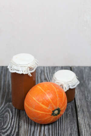 Orange pumpkin and pumpkin jam in jars. On brushed pine boards painted black and white.の写真素材