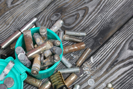 Corroded used batteries. They lie in and around the trash can. Disposal of hazardous waste.