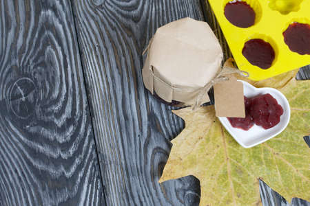 A jar of cherry jam with a label for an inscription and a saucer of cherry marmalade. A silicone...