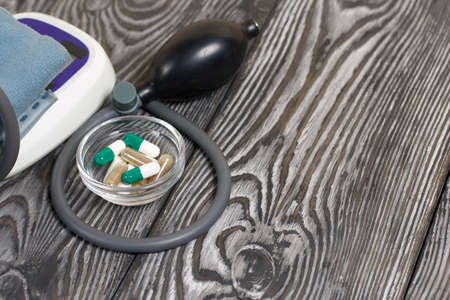 Tonometer and a handful of pills. To control blood pressure. Diagnostics and treatment of cardiovascular diseases.の写真素材