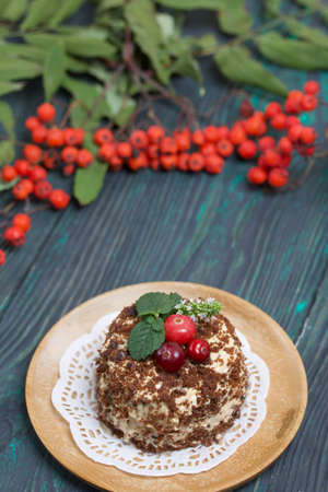 Sponge cake with butter cream. Decorated with cranberries and mint. Nearby are rowan branches with...