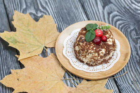 Sponge cake with butter cream. Decorated with cranberries and mint. Nearby are dried maple leaves....