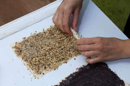 A woman rolls up the rolled dough with a layer of walnuts. Cooking buns.