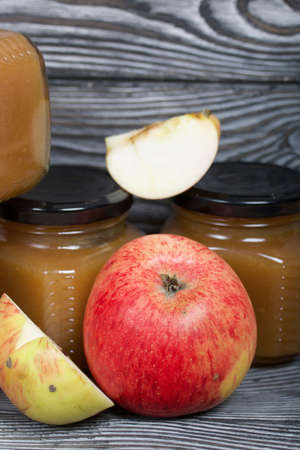 Apple jam in jars. Nearby are apple slices. On brushed boards, painted black and white.の写真素材
