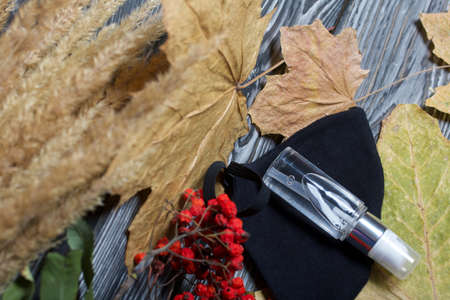 Medical mask and antiseptic. Nearby is a rowan branch, a bouquet of dried grass and maple leaves. On...