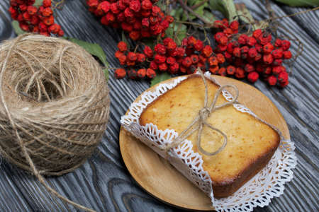 Freshly baked cupcake on a napkin. Tied with twine. Nearby is a dried rowan branch with red berries...