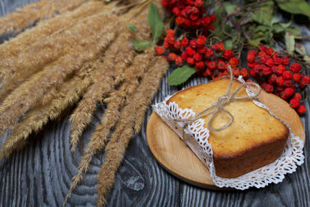 Freshly baked cupcake on a napkin. Tied with twine. Nearby is a dried rowan branch with red berries...