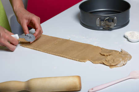 The woman cuts the rolled dough. Cooking tools are nearby. Levington cake, stages of preparation.