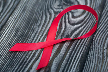 Red Ribbon Symbol for World AIDS Day. Lies on black pine boards.の写真素材