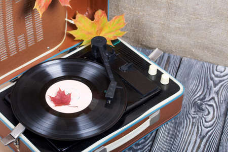 Old turntable with autumn maple leaves. Retro party equipment.