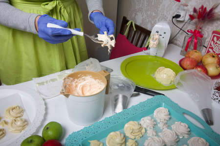 A woman in rubber gloves and a medical mask works with a marshmallow mass. Fresh marshmallows are...