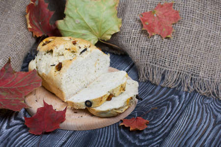 Focaccia bread with olives and sun-dried tomatoes. Nearby are linen and dried autumn leaves. On pine...