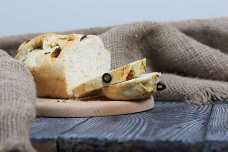 Focaccia bread with olives and sun-dried tomatoes. Linen is nearby. On pine boards.