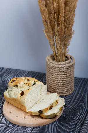 Focaccia bread with olives and sun-dried tomatoes. Nearby is a bouquet of dried grass. On pine...
