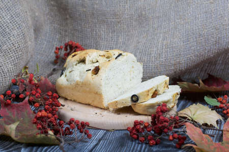 Focaccia bread with olives and sun-dried tomatoes. Nearby are linen and dried autumn leaves. On pine...