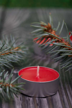 Branches of blue spruce on brushed pine boards. Nearby is a red candle. Close-up shot.の写真素材