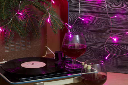 Old turntable. There are glasses of wine nearby. Spruce branches and burning festive garlands....