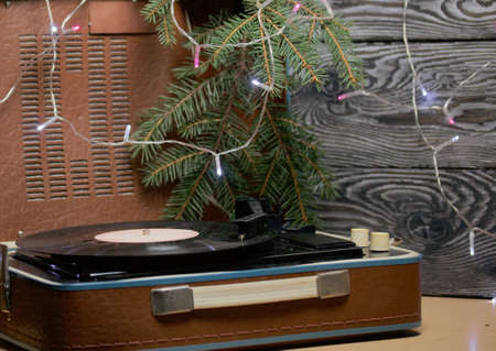 Old turntable. Nearby there are spruce branches and burning festive garlands. Against the background...