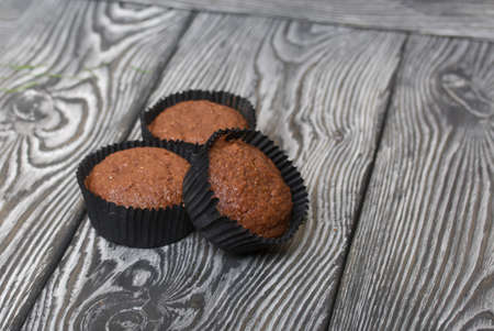Oatmeal chocolate muffins. Drawn up on a silver platter. One is broken to show a cut. On black pine boards.の写真素材