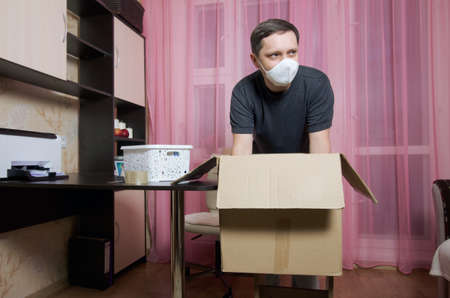 The man puts things in a cardboard box. Moving to a new place of residence.
