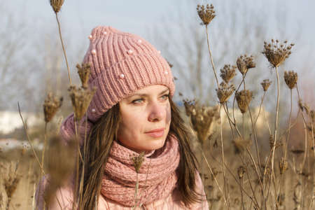 A girl in autumn clothes among the dried tall grass. Walking in nature in the park.の写真素材