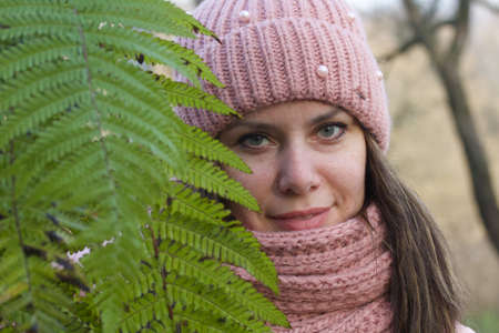 Girl in autumn clothes. Walking in nature in the park. Holds green branches of a fern in his hands. Close-up shot.の写真素材